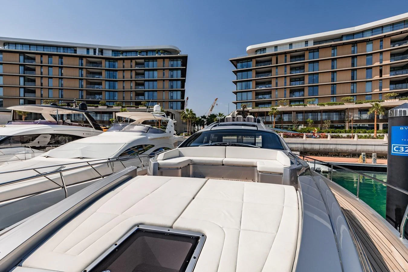 The yacht is docked in a modern marina with luxury buildings in the background. aboard 2021 PERSHING 8X Yacht for Sale