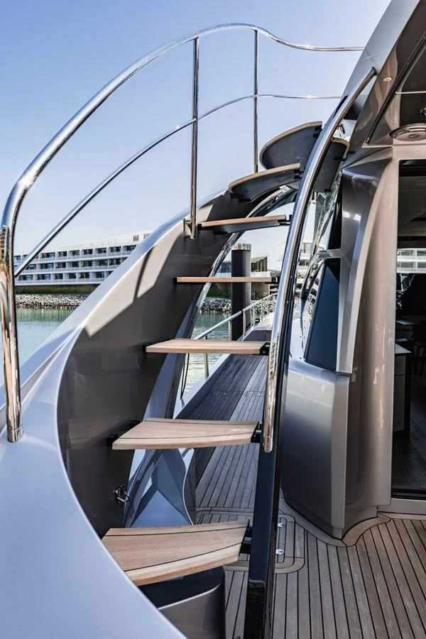 A sleek staircase with wooden steps and polished metal railings leads to the upper deck. aboard 2021 PERSHING 8X Yacht for Sale