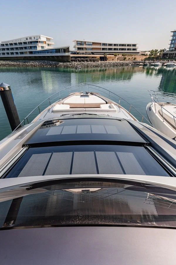 The yacht is docked in a serene marina with modern buildings in the background. aboard 2021 PERSHING 8X Yacht for Sale