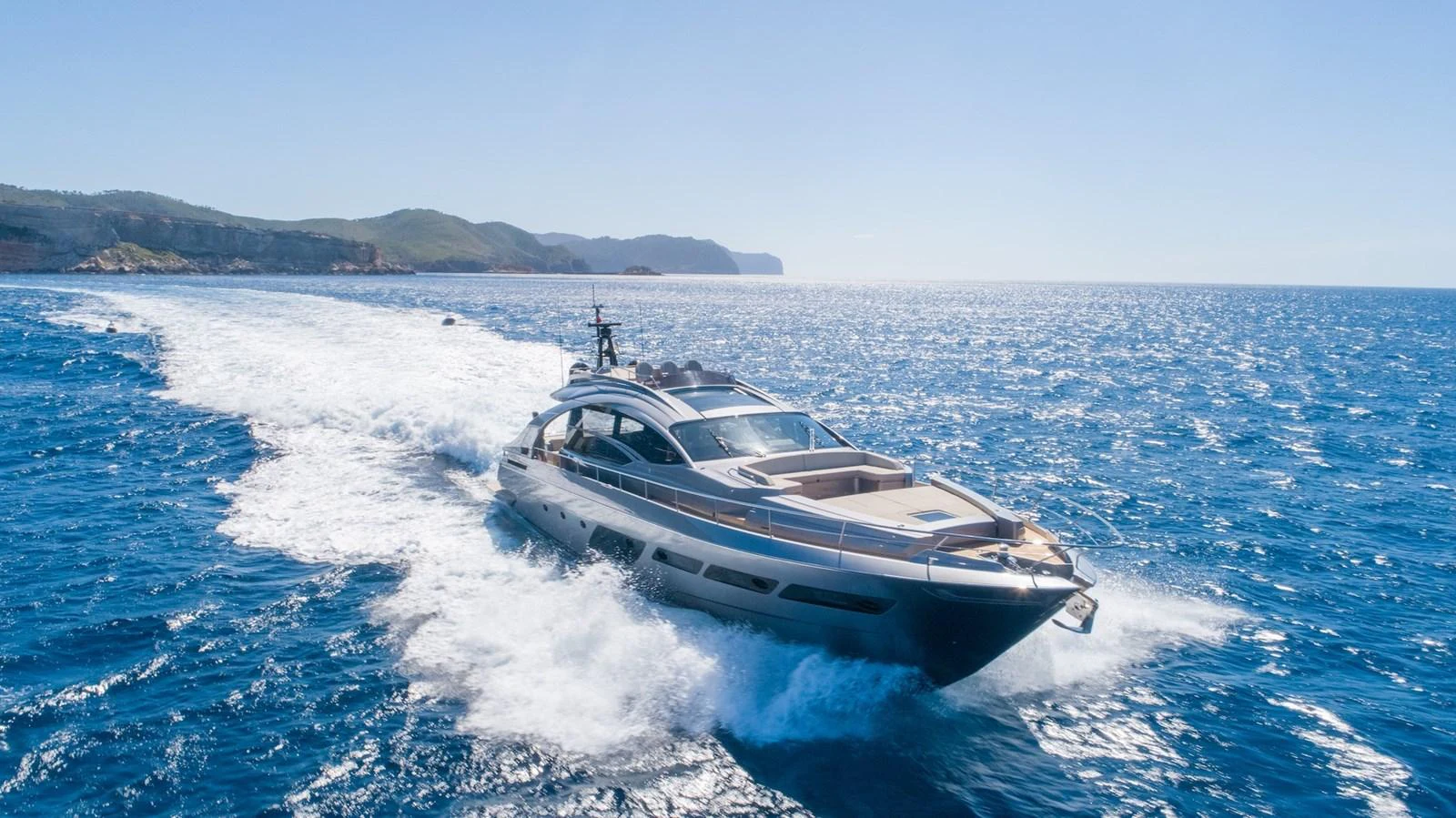 A sleek yacht cruises swiftly through the open sea under a clear blue sky. aboard DESERT STAR Yacht for Sale