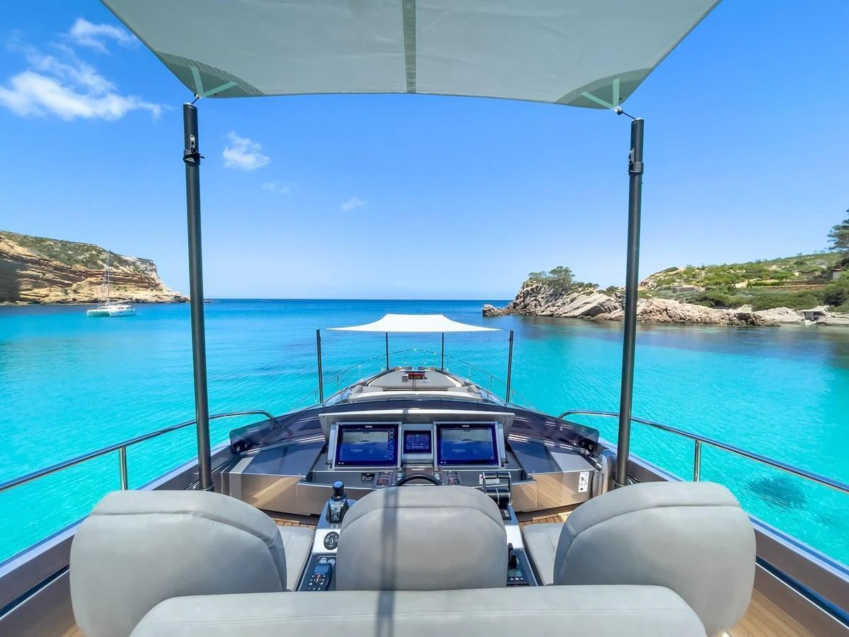 The helm station offers a stunning view of turquoise waters and a serene coastline. aboard DESERT STAR Yacht for Sale