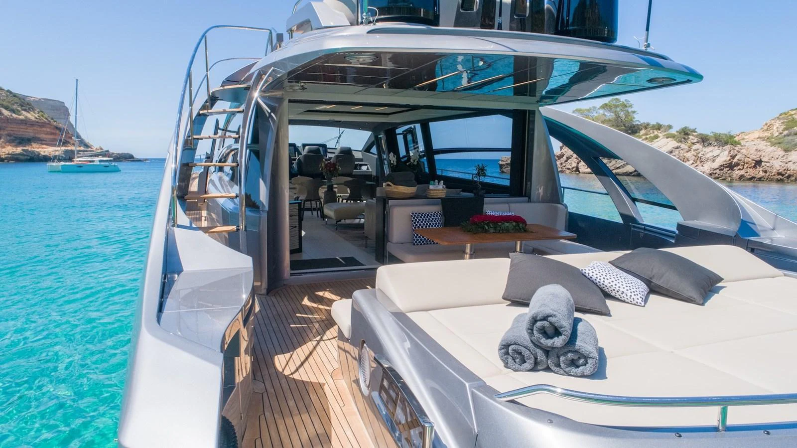 The yacht's aft deck features a luxurious lounging area with plush seating and a dining space, all set against a stunning ocean backdrop. aboard DESERT STAR Yacht for Sale