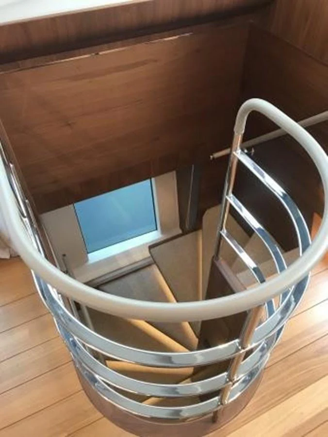 A sleek, modern staircase with wooden steps and metal railings leads to the lower deck. aboard ANDAMAN PRINCESS Yacht for Sale