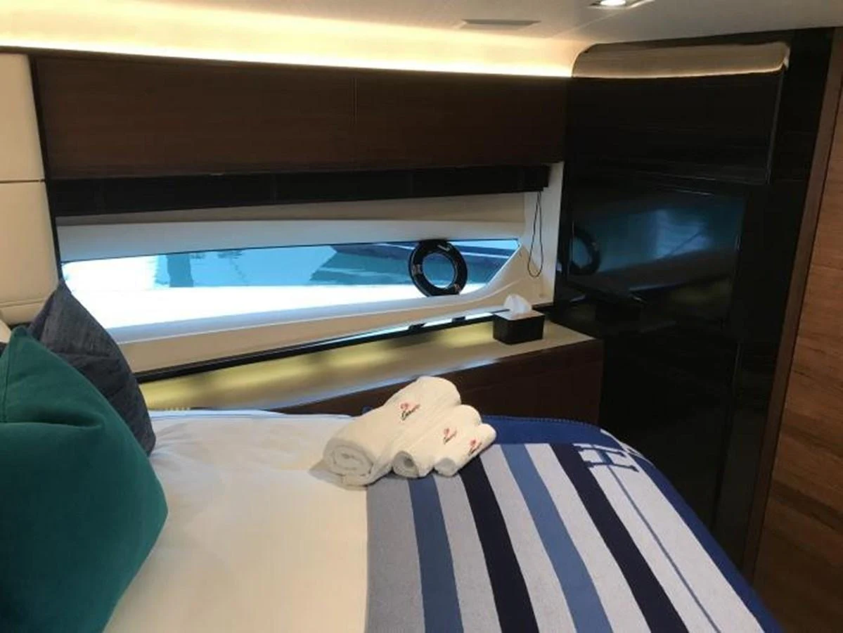 A cozy stateroom featuring a neatly made bed with striped bedding and a window view. aboard ANDAMAN PRINCESS Yacht for Sale