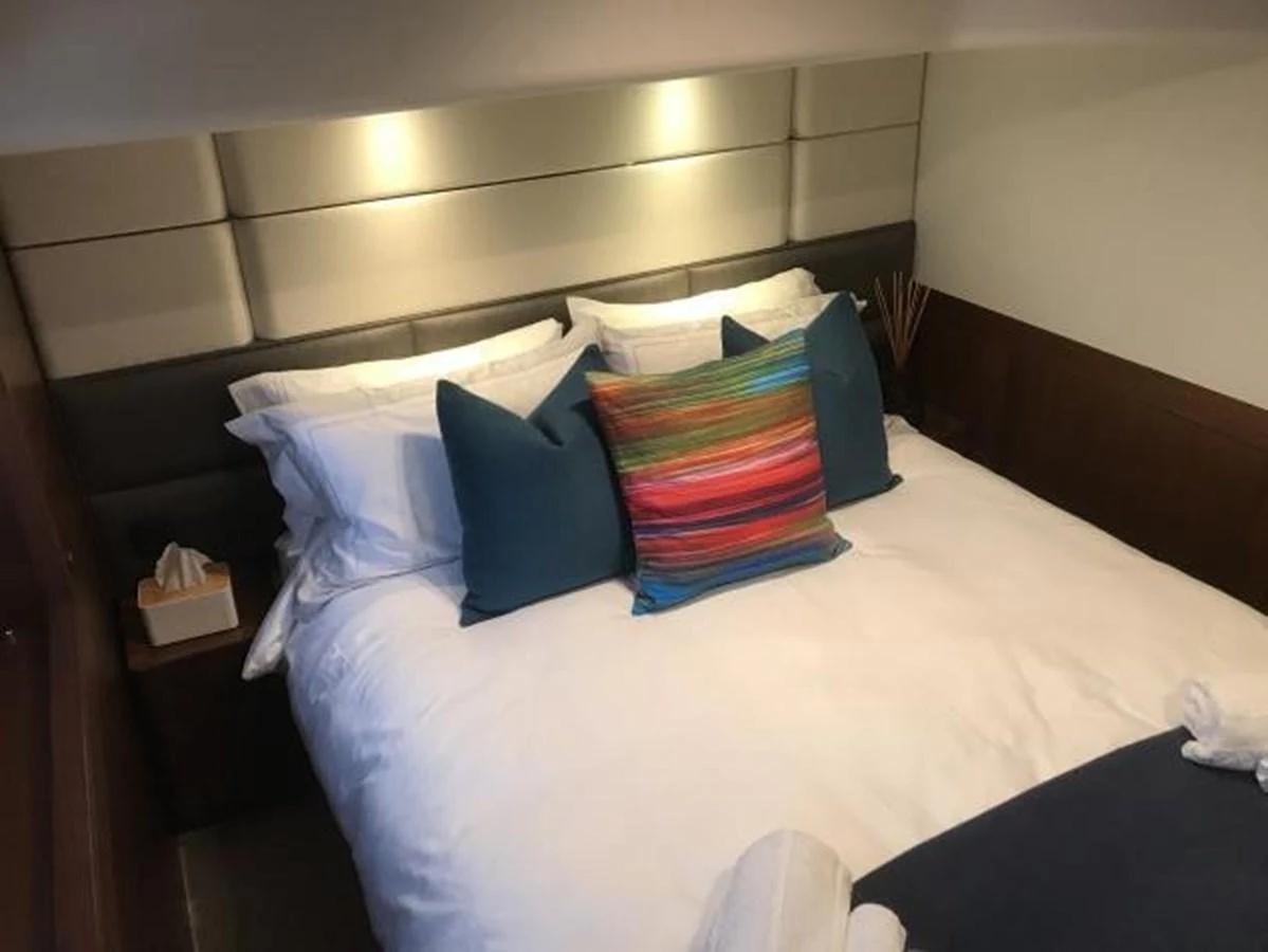 A cozy stateroom featuring a plush bed with colorful pillows and modern lighting. aboard ANDAMAN PRINCESS Yacht for Sale