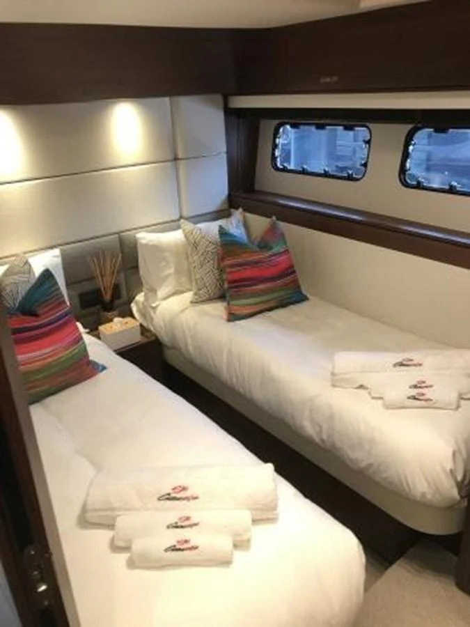 A cozy twin stateroom featuring two single beds with colorful pillows and neatly arranged towels. aboard ANDAMAN PRINCESS Yacht for Sale