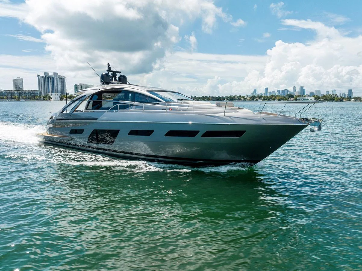 A sleek yacht cruises through calm waters with a cityscape in the background. aboard QUANTUM Yacht for Sale