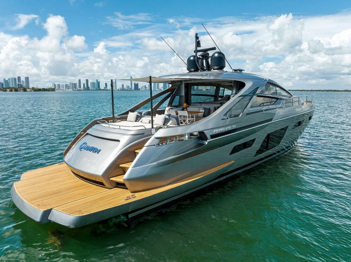 A sleek yacht cruises on calm waters with a city skyline in the background. aboard QUANTUM Yacht for Sale