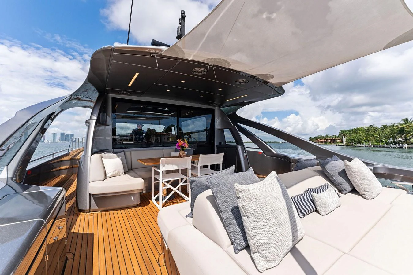 The aft deck features a comfortable seating area with plush cushions and a dining table under a shaded canopy. aboard QUANTUM Yacht for Sale