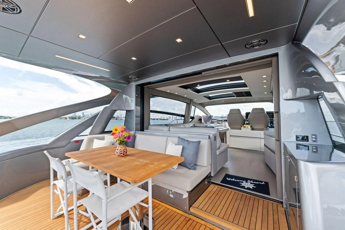 The aft deck features a stylish dining area with a wooden table and comfortable seating, seamlessly connecting to the interior. aboard QUANTUM Yacht for Sale