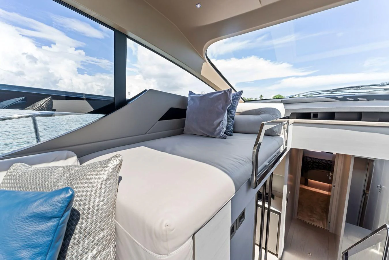 A cozy interior space featuring a comfortable bed with plush pillows and a view of the water through large windows. aboard QUANTUM Yacht for Sale