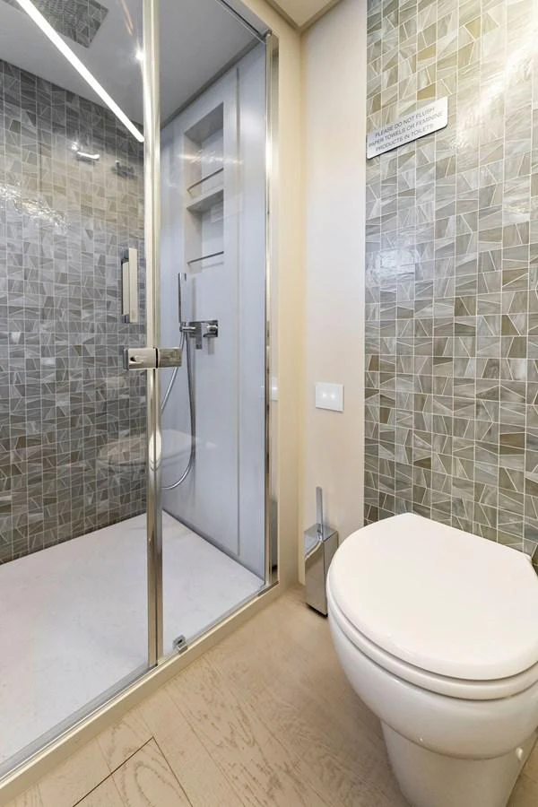 A modern yacht bathroom featuring a glass-enclosed shower and a sleek toilet. aboard QUANTUM Yacht for Sale
