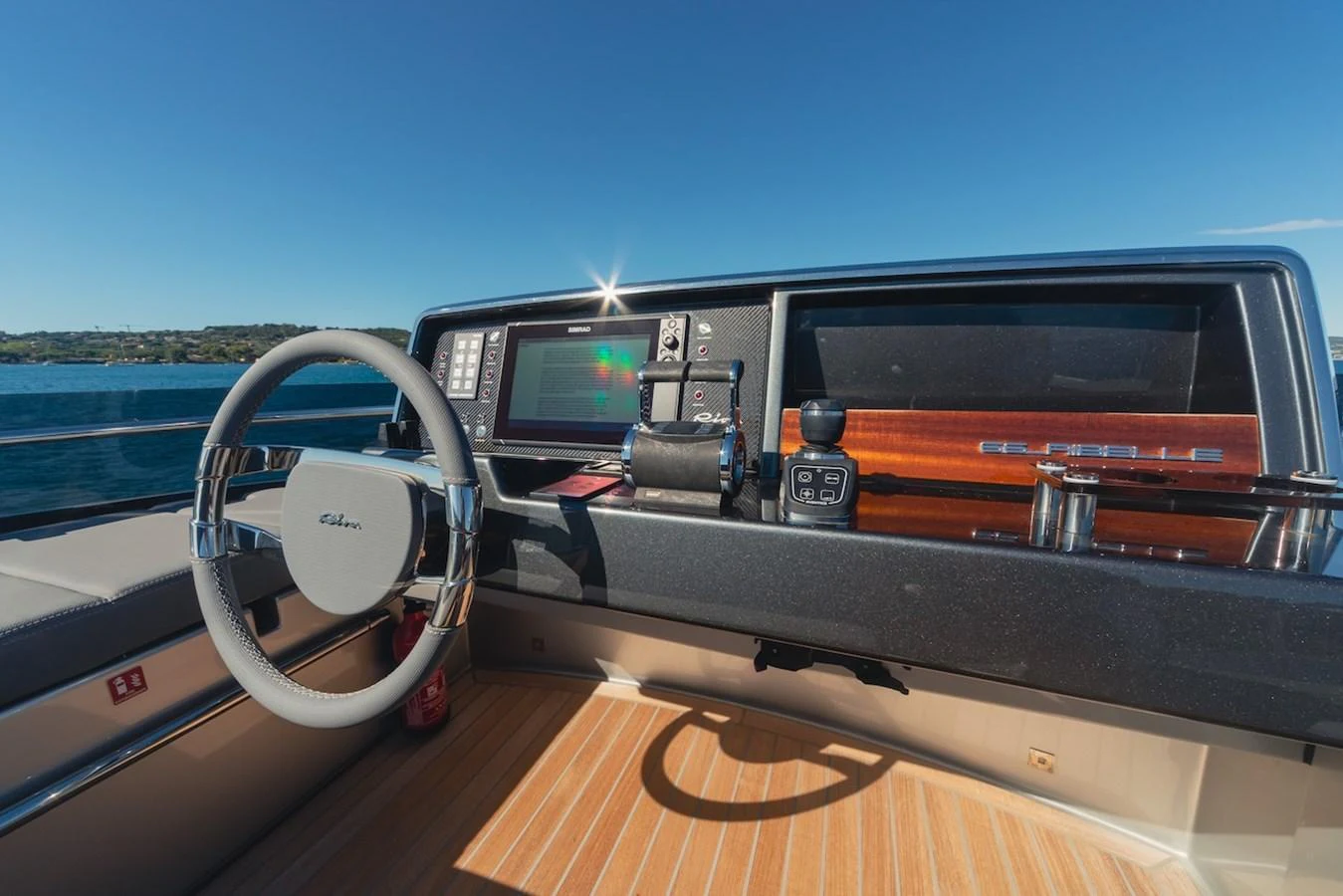 The helm station features modern navigation equipment and a sleek steering wheel, set against a backdrop of clear blue skies and calm waters. aboard AMELIA Yacht for Sale