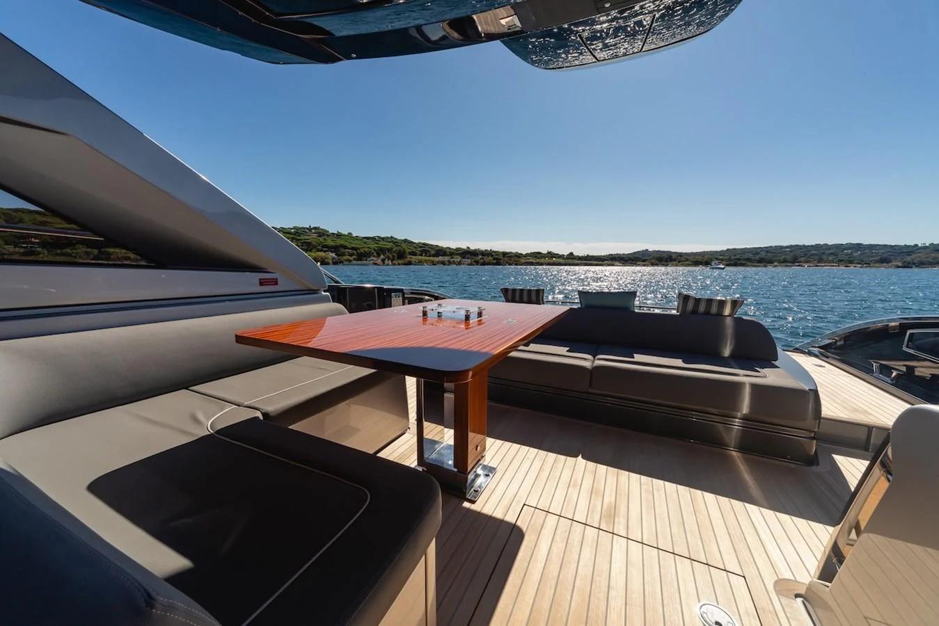 The aft deck features a spacious seating area with a sleek wooden table, perfect for alfresco dining with stunning sea views. aboard AMELIA Yacht for Sale