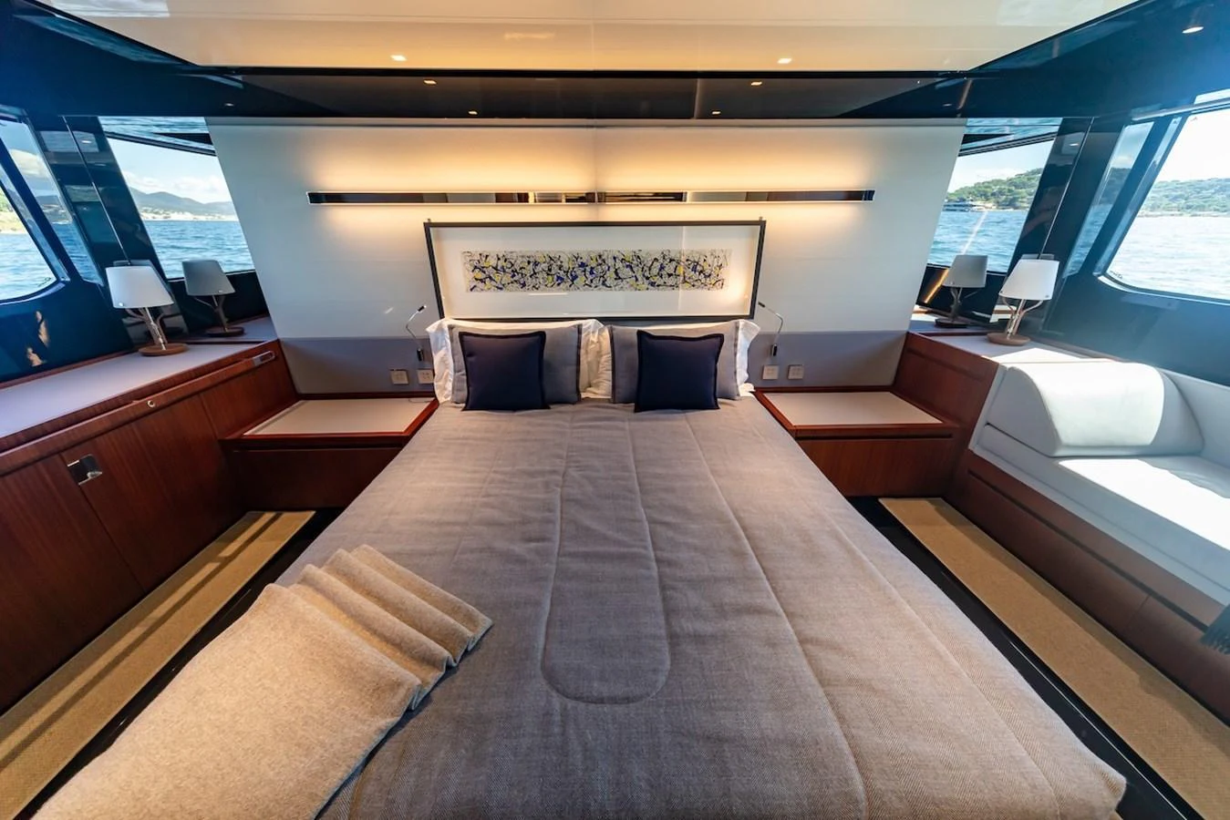 The master stateroom features a luxurious bed with elegant bedding and ample natural light from large windows. aboard AMELIA Yacht for Sale