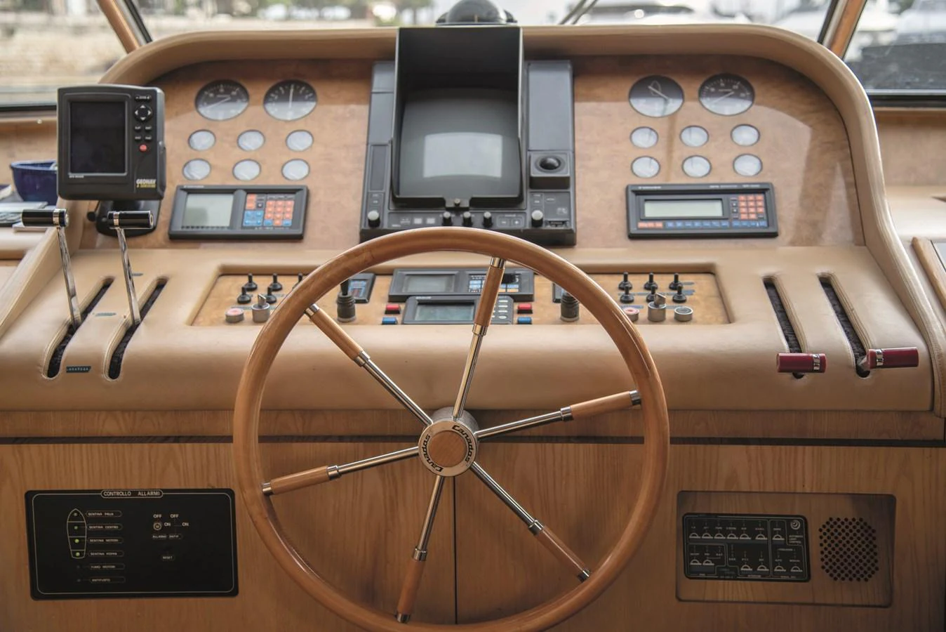 The helm station features a classic wooden steering wheel and an array of navigational instruments. aboard KISS Yacht for Sale