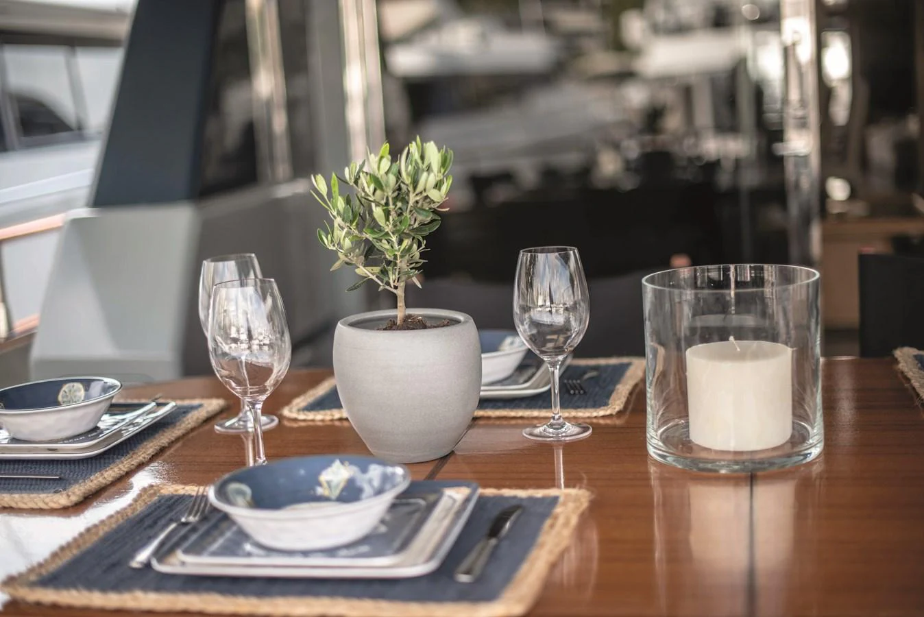 A beautifully set dining table with elegant tableware and a small potted plant, creating a refined ambiance. aboard KISS Yacht for Sale