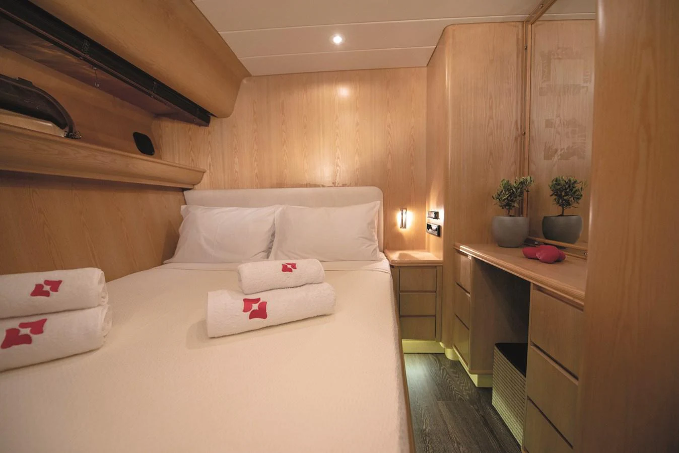 The guest stateroom offers a cozy and inviting space with warm wood finishes and modern amenities. aboard KISS Yacht for Sale