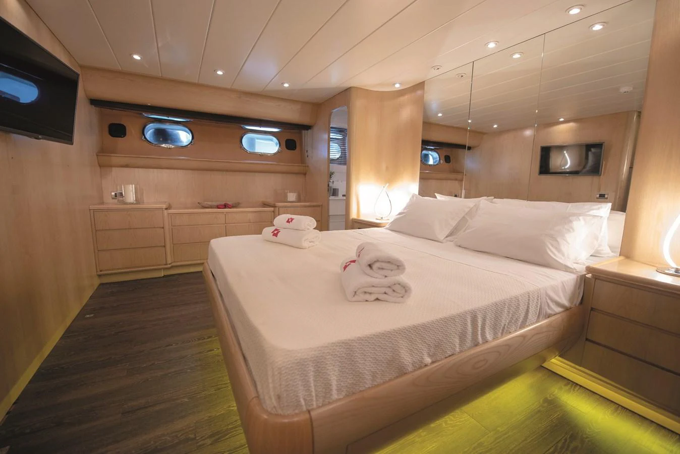 The master stateroom features a spacious bed, warm wood finishes, and modern lighting. aboard KISS Yacht for Sale