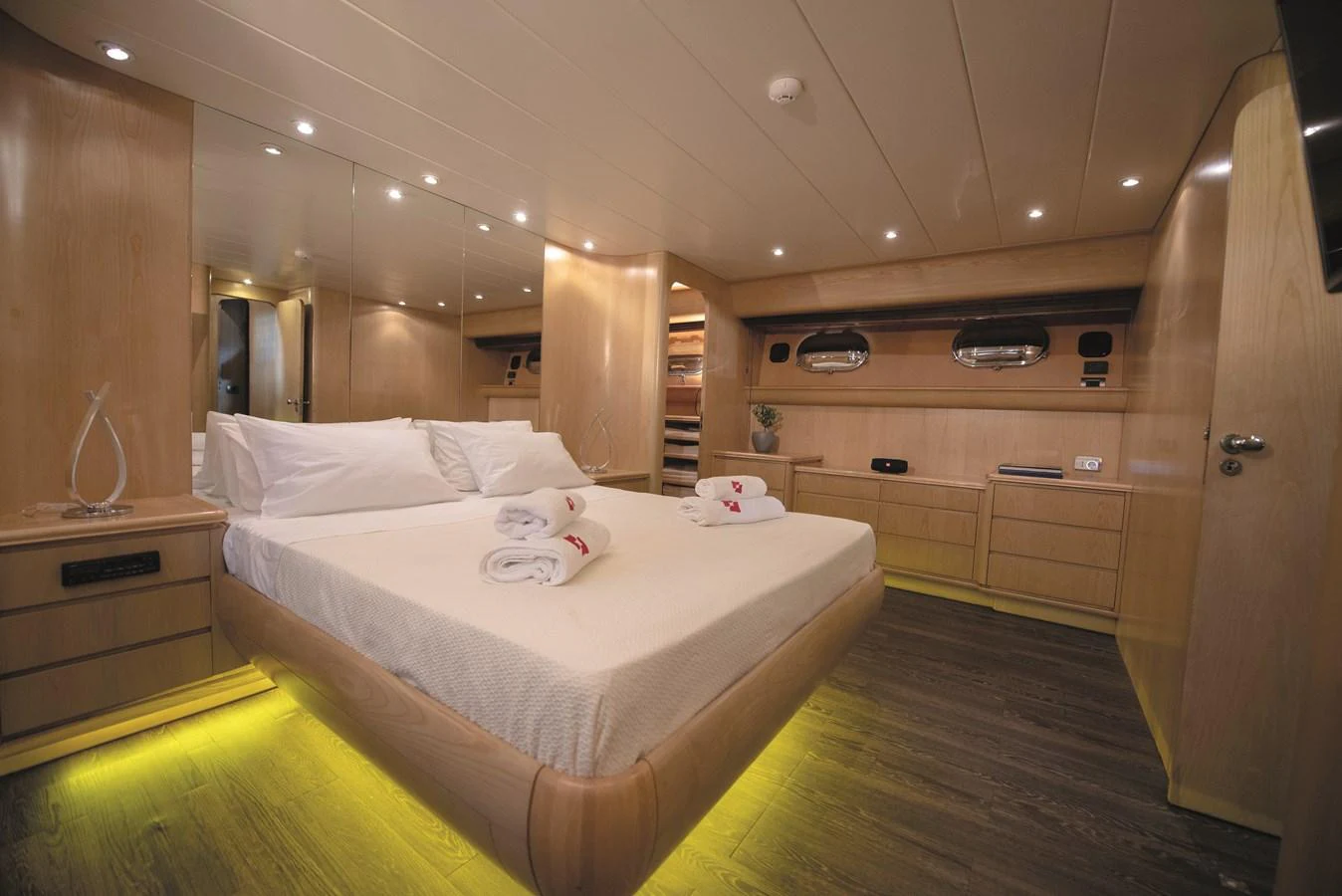 The master stateroom features a spacious bed, ambient lighting, and elegant wood finishes. aboard KISS Yacht for Sale