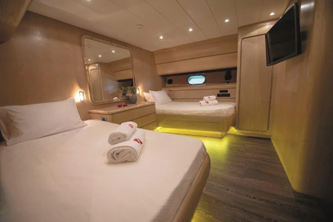 The guest stateroom features two comfortable beds with modern lighting and a sleek design. aboard KISS Yacht for Sale