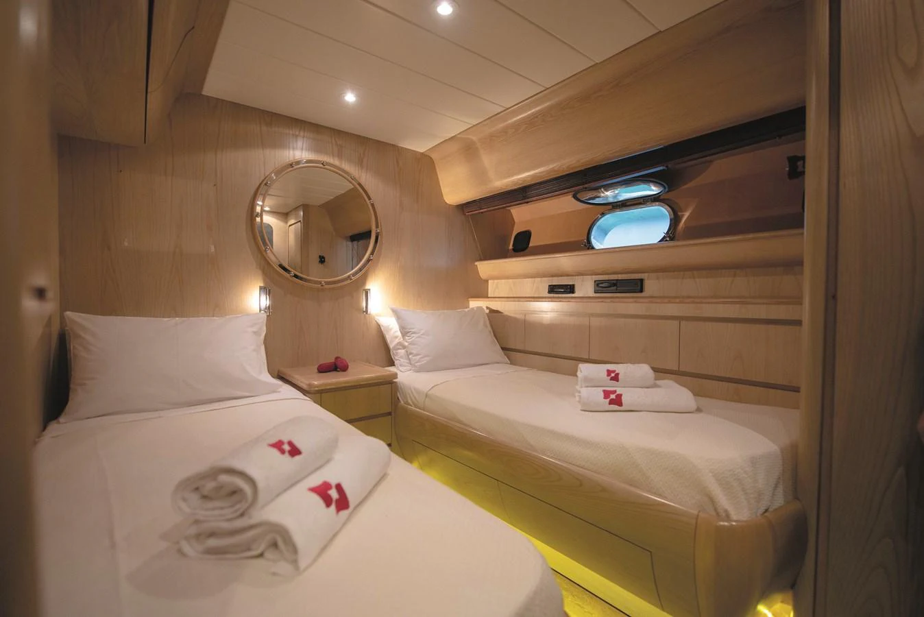The twin stateroom offers a cozy and inviting space with two single beds and warm wood finishes. aboard KISS Yacht for Sale