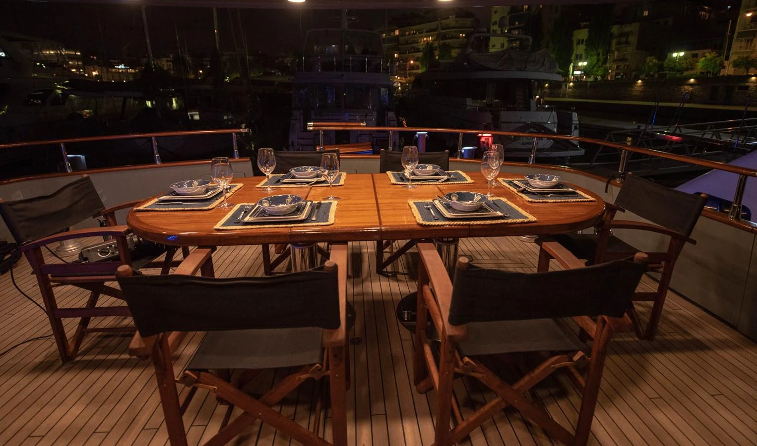 An elegant dining area on the yacht, set for an evening meal with a view of the marina. aboard KISS Yacht for Sale