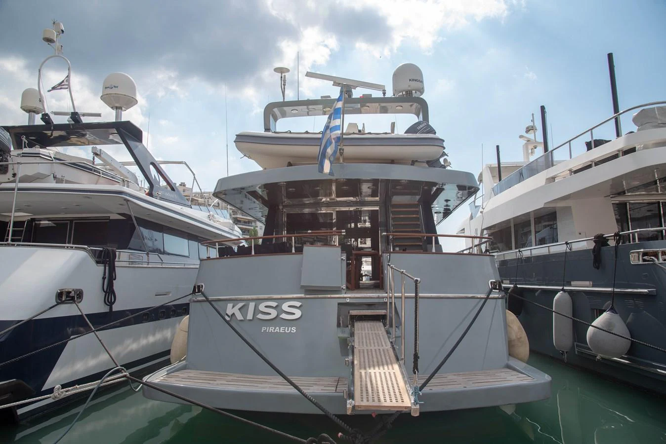 The yacht is docked at a marina, showcasing its sleek aft deck and modern design. aboard KISS Yacht for Sale