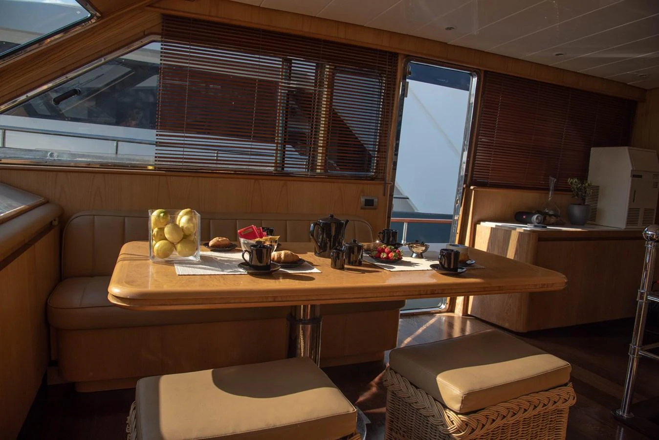 The yacht's dining area features a cozy table set for breakfast, bathed in natural light from large windows. aboard KISS Yacht for Sale
