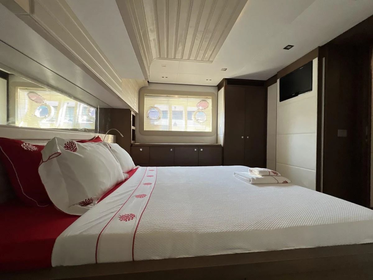 a bed with a white sheet and pink pillows aboard NGV Yacht for Sale