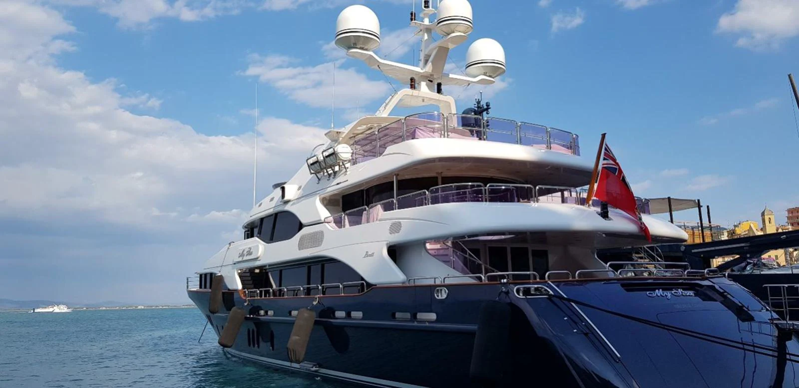 A luxurious yacht docked in a serene harbor under a clear blue sky. aboard MY SISA Yacht for Sale