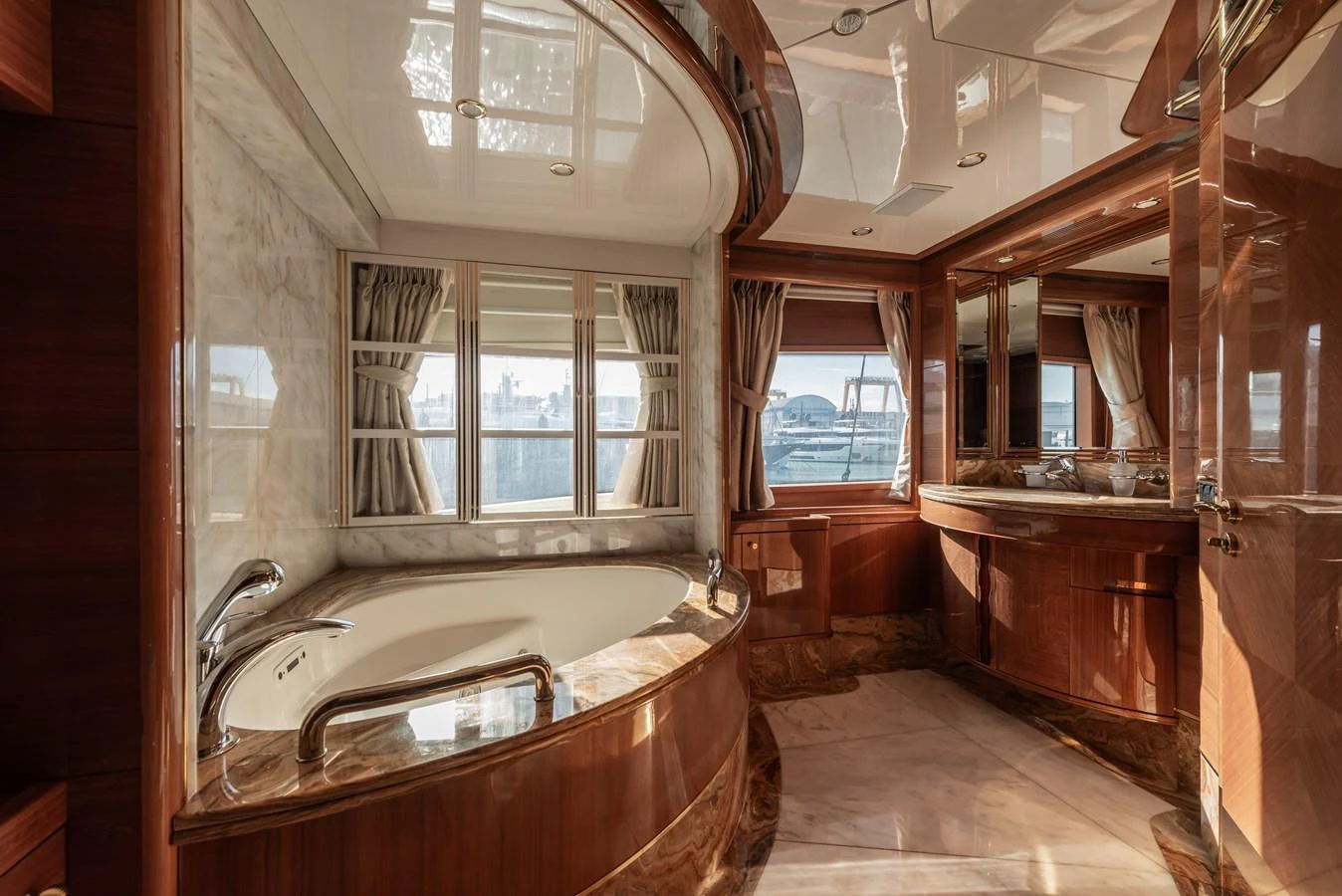 The yacht's bathroom features luxurious wood finishes and a large soaking tub with a view. aboard MY SISA Yacht for Sale