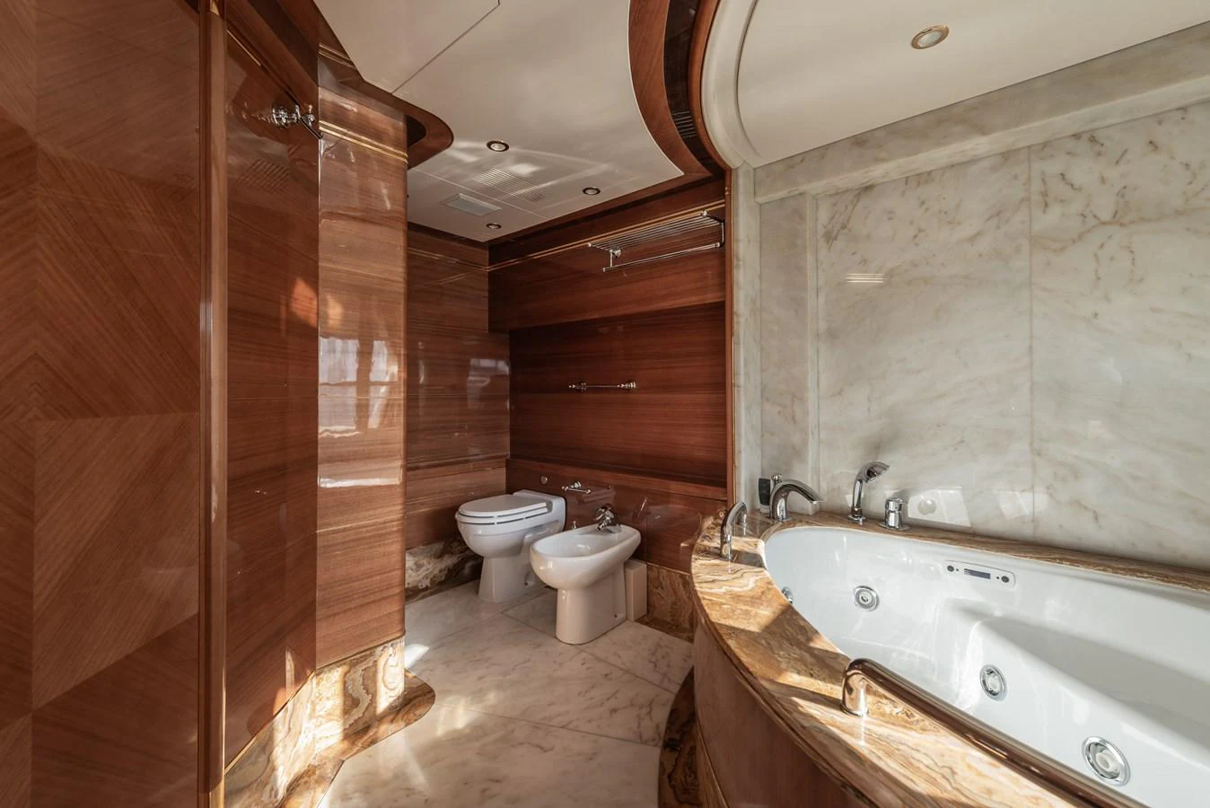 The luxurious bathroom features elegant wood paneling and a spacious jacuzzi tub. aboard MY SISA Yacht for Sale