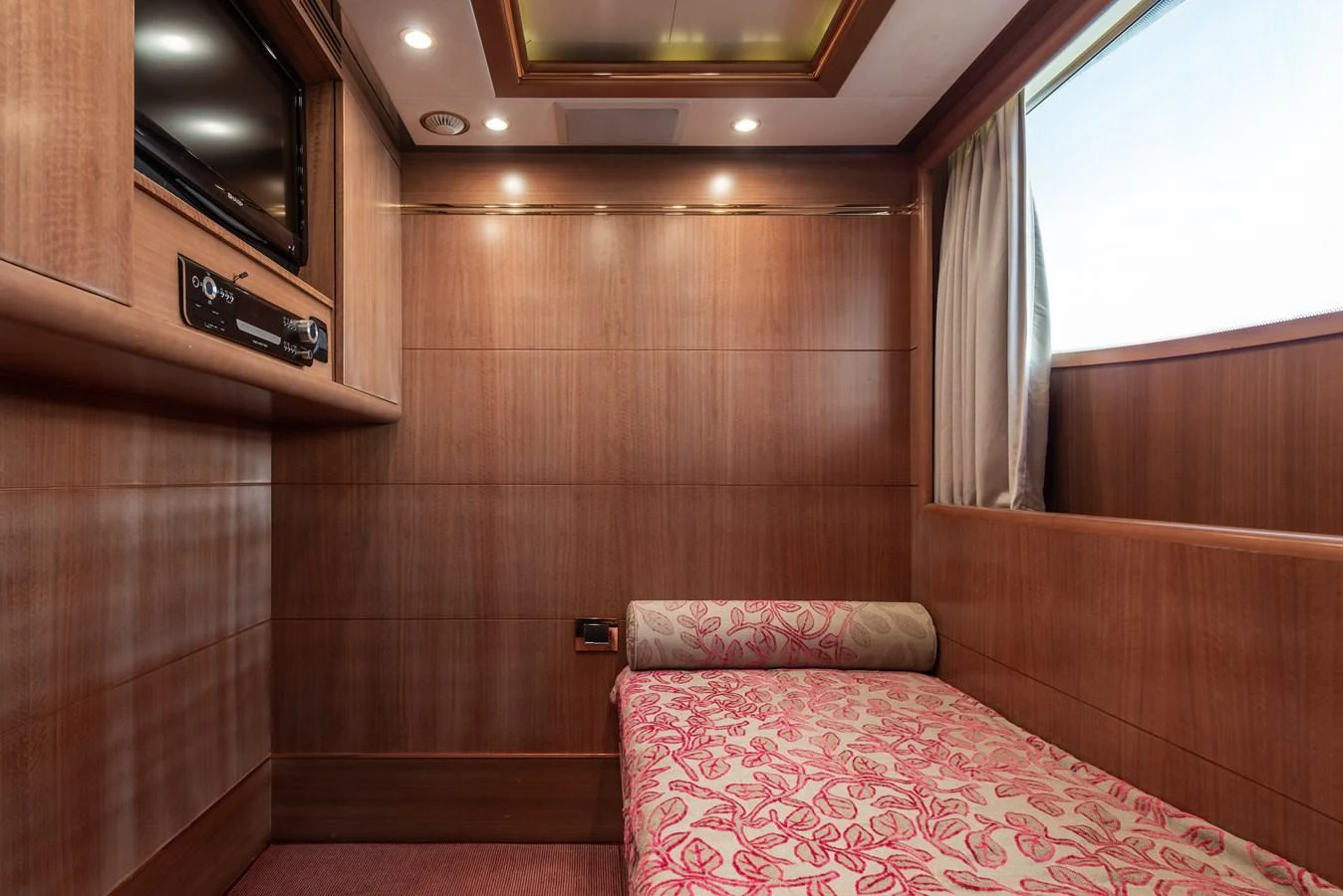 A cozy stateroom with wood paneling and a single bed adorned with a floral bedspread. aboard MY SISA Yacht for Sale