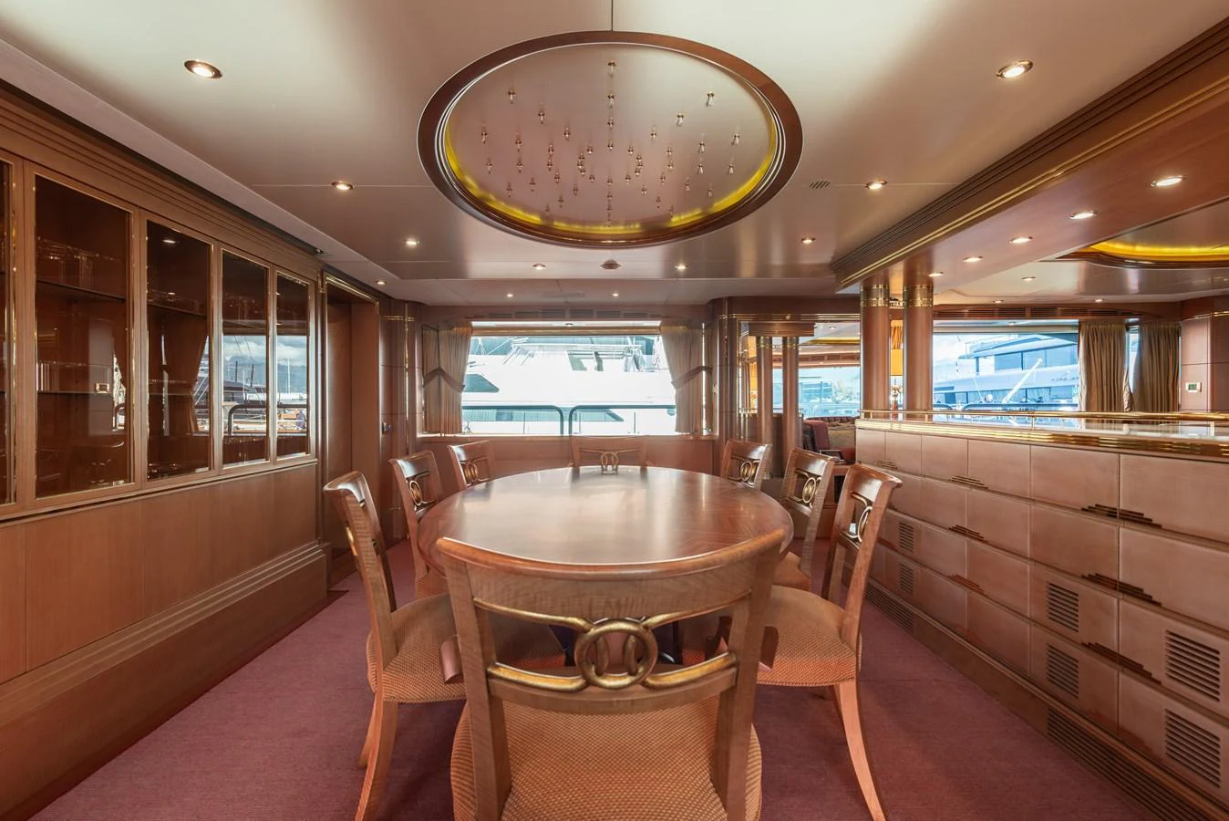 The yacht's dining area features a large wooden table surrounded by elegant chairs, under a beautifully lit ceiling. aboard MY SISA Yacht for Sale