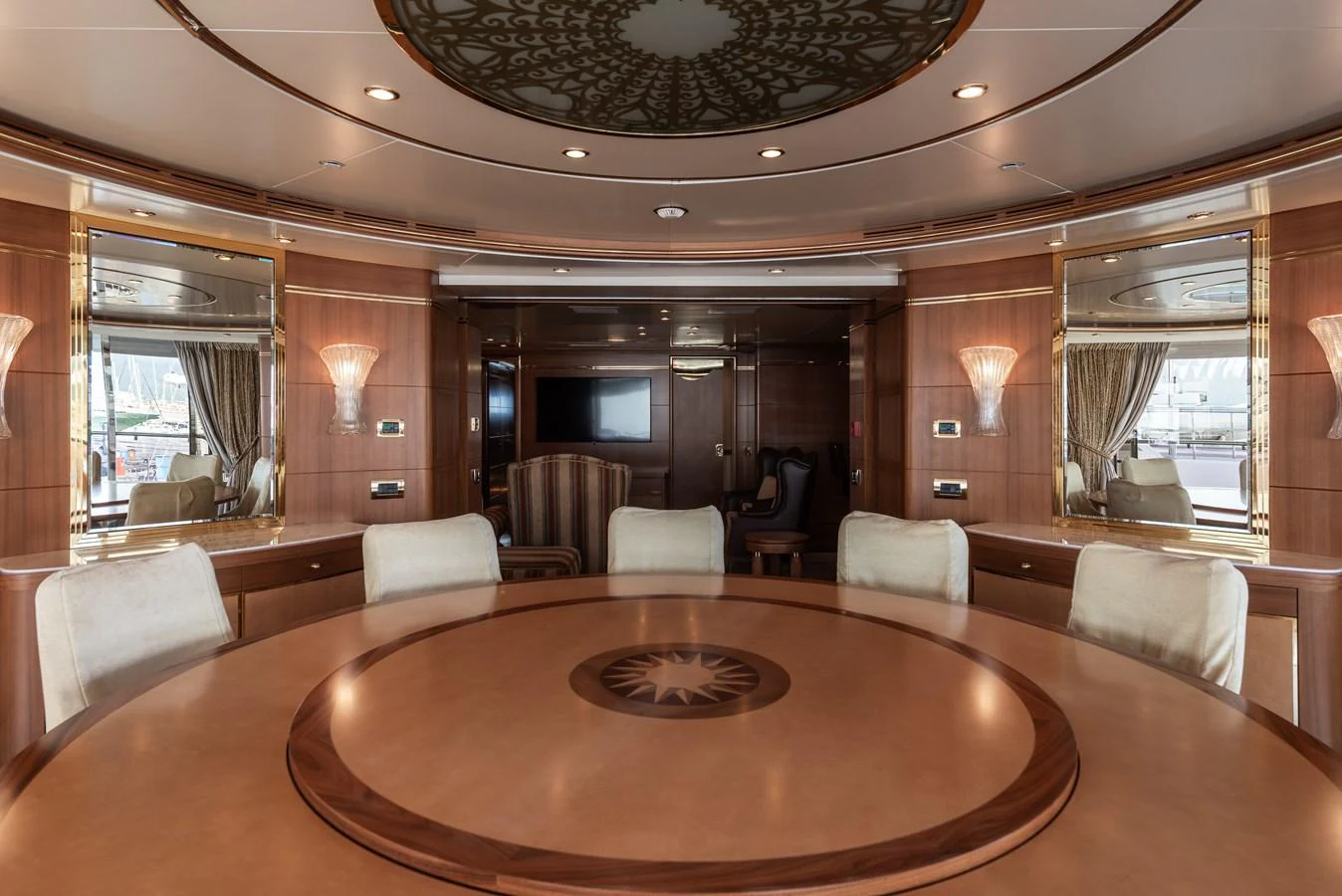 The yacht's dining area features a large round table with elegant woodwork and plush seating. aboard MY SISA Yacht for Sale