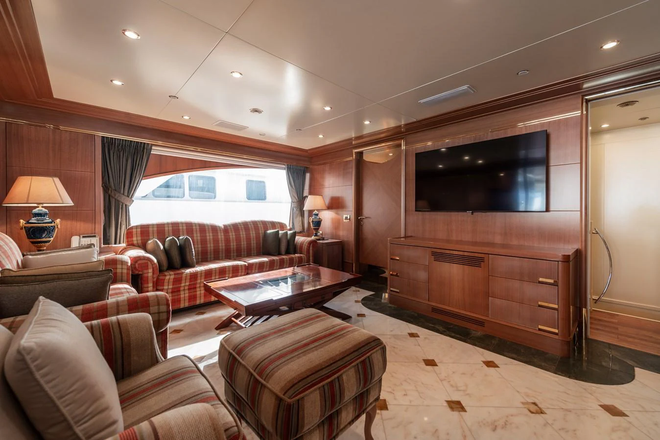 The salon features elegant wood paneling, plush seating, and a large flat-screen TV, creating a cozy and inviting atmosphere. aboard MY SISA Yacht for Sale