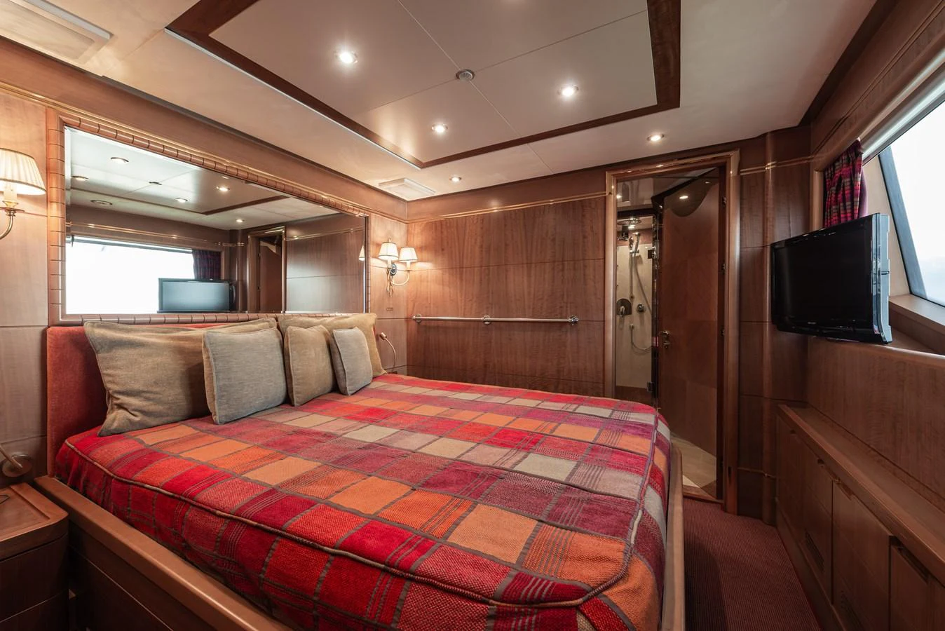 The stateroom features a cozy bed with a plaid blanket, warm wood paneling, and modern amenities. aboard MY SISA Yacht for Sale