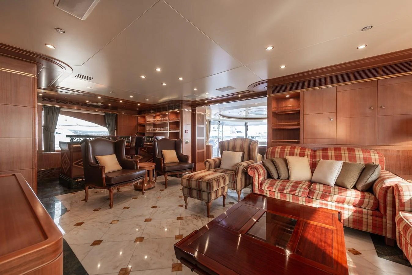 The yacht's salon features luxurious seating with elegant wood finishes and ample natural light. aboard MY SISA Yacht for Sale