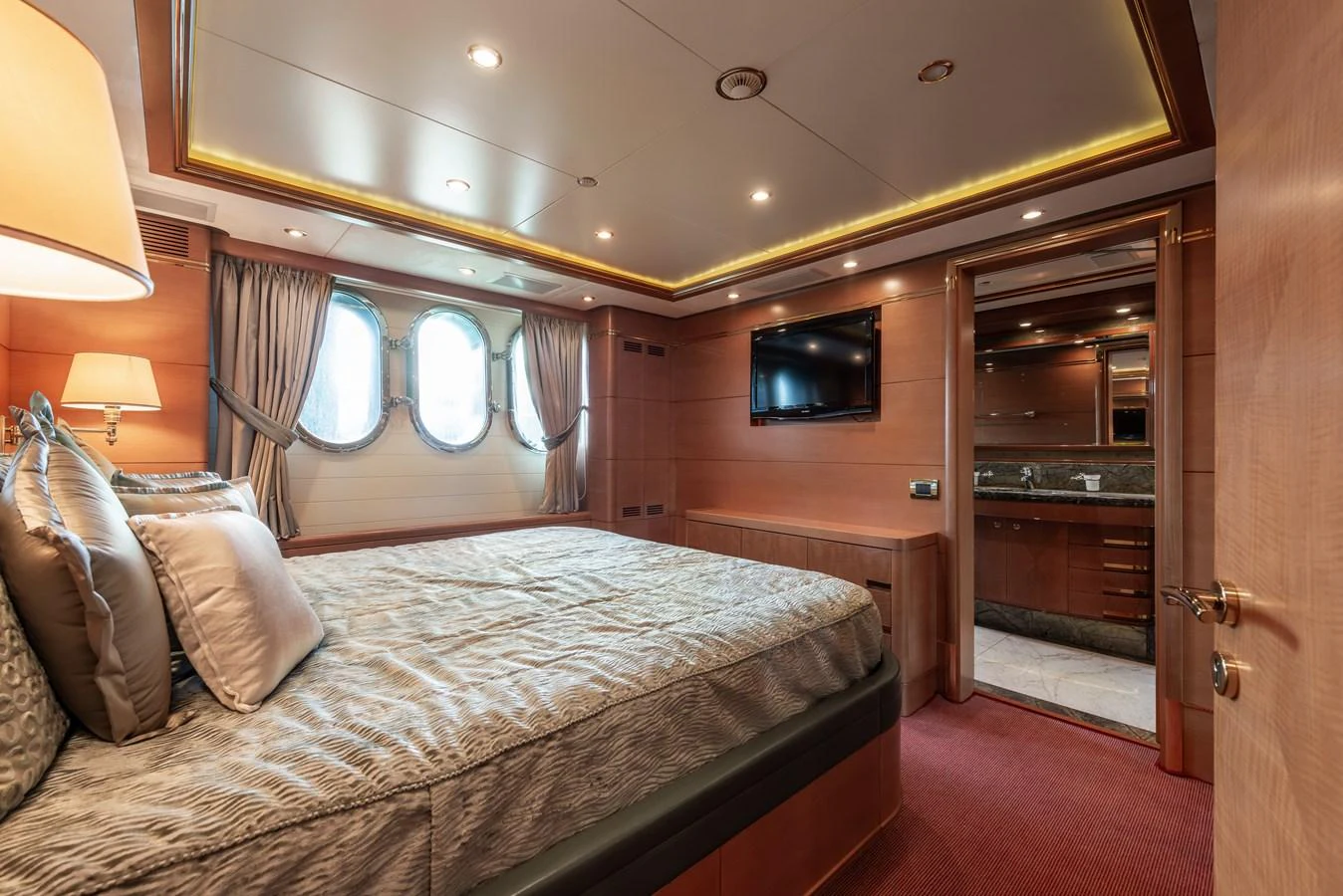 The stateroom features a luxurious bed, elegant wood paneling, and an en-suite bathroom. aboard MY SISA Yacht for Sale