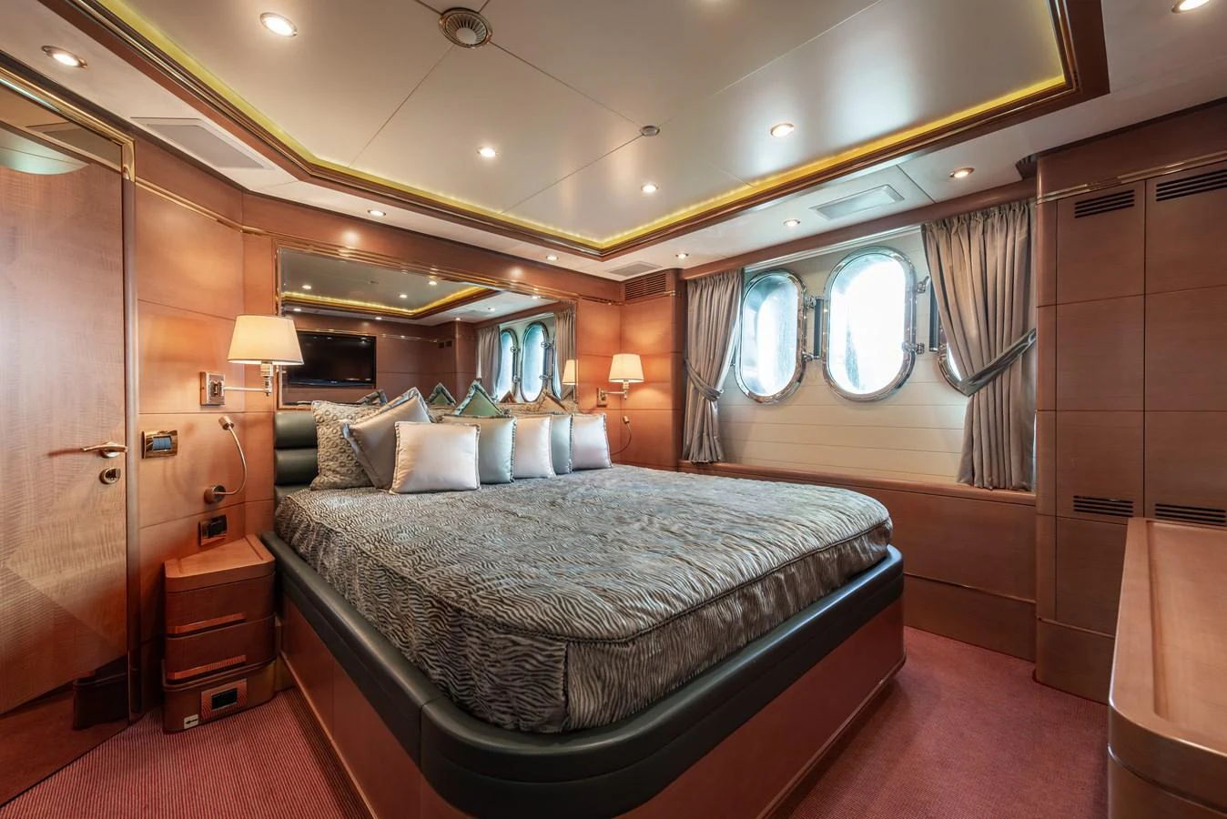 The master stateroom features a luxurious bed with elegant decor and ample natural light from the porthole windows. aboard MY SISA Yacht for Sale