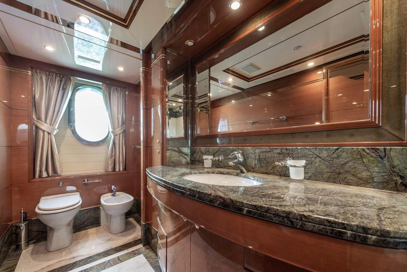 The yacht's bathroom features elegant wood paneling, a marble countertop, and a large mirror, creating a luxurious and refined atmosphere. aboard MY SISA Yacht for Sale