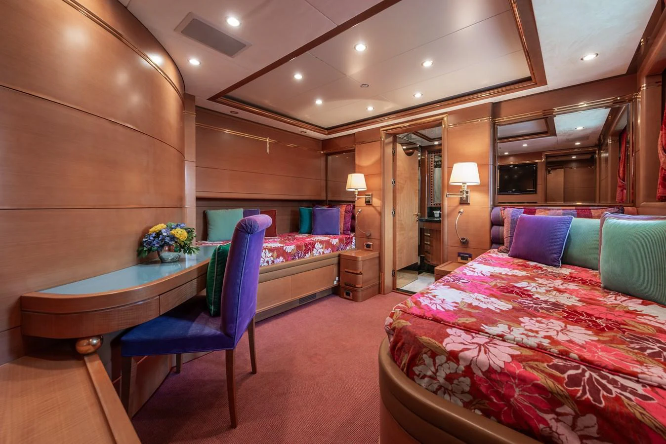 A luxurious guest stateroom with vibrant bedding and elegant wooden finishes. aboard MY SISA Yacht for Sale