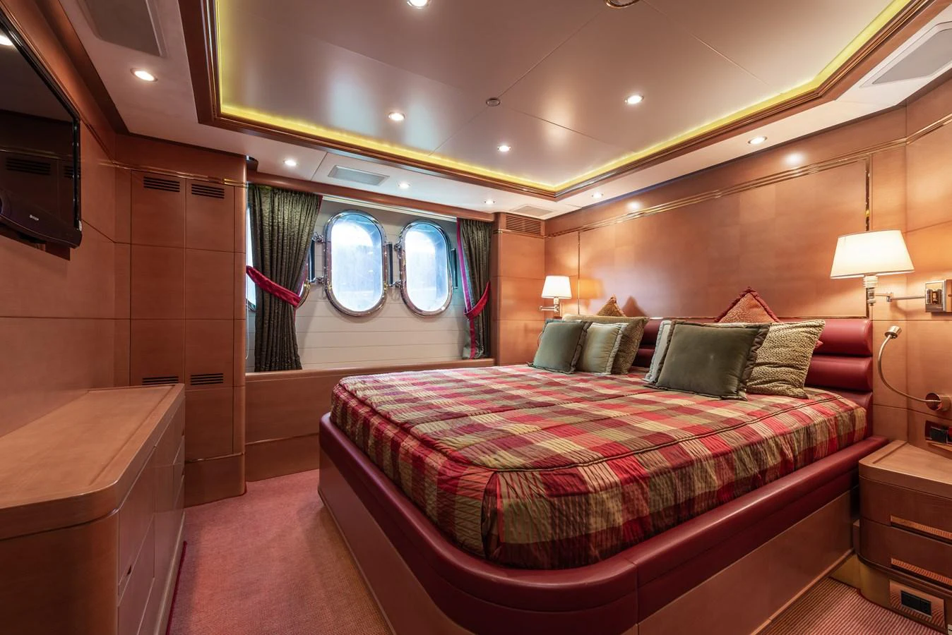 The stateroom features a large bed with elegant bedding and ample natural light from the porthole windows. aboard MY SISA Yacht for Sale
