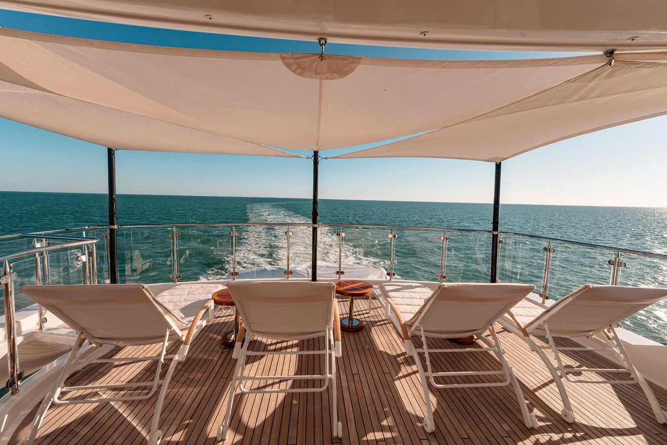 a deck with chairs and tables on it by the ocean aboard BLUE TIME Yacht for Sale