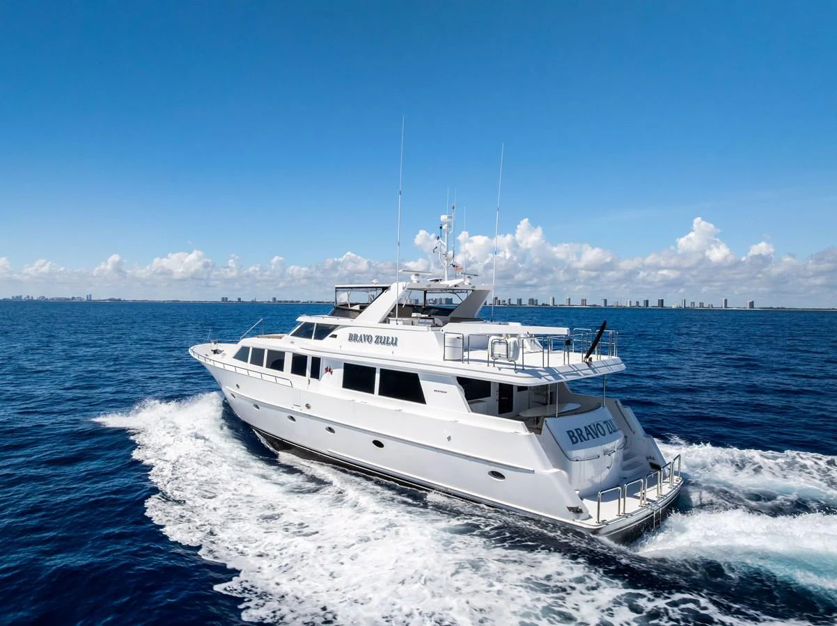 A sleek yacht cruises through the open sea under a clear blue sky. aboard BRAVO ZULU Yacht for Sale