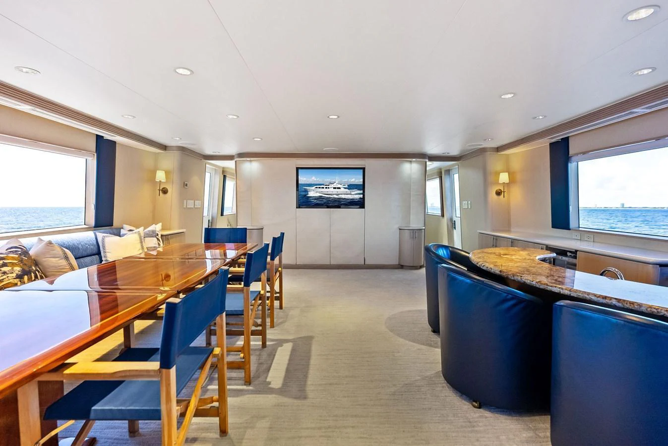 The spacious salon features a comfortable seating area, a dining table, and large windows offering panoramic ocean views. aboard BRAVO ZULU Yacht for Sale