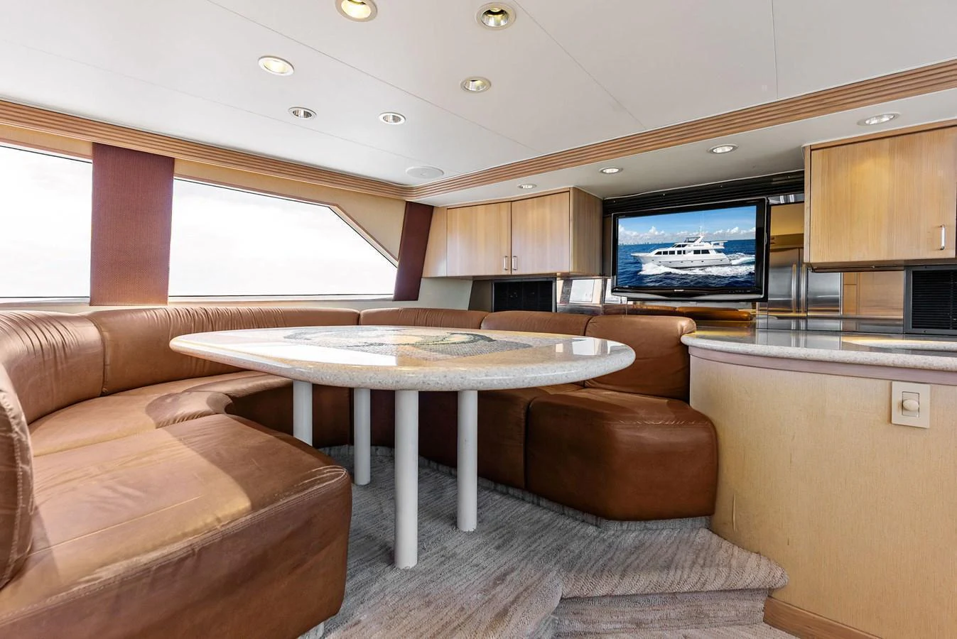 The saloon features a comfortable seating area with a round table and a flat-screen TV. aboard BRAVO ZULU Yacht for Sale