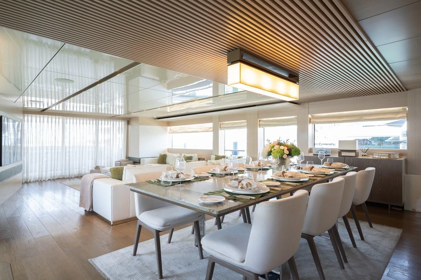 The yacht's dining area features a modern table set for a meal, surrounded by comfortable chairs and bathed in natural light. aboard M/Y MASHA Yacht for Sale