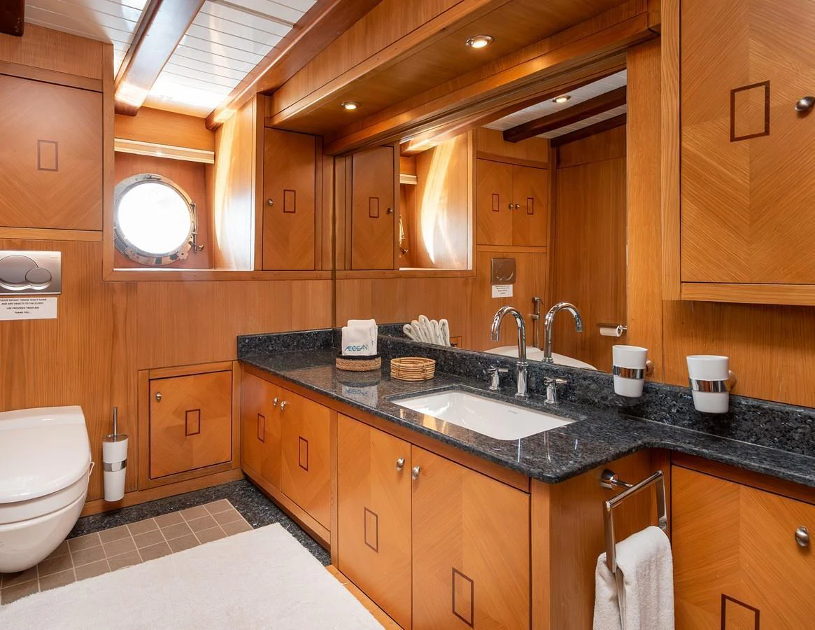 The yacht's bathroom features elegant wooden cabinetry and a sleek countertop with modern fixtures. aboard AEGEAN Yacht for Sale